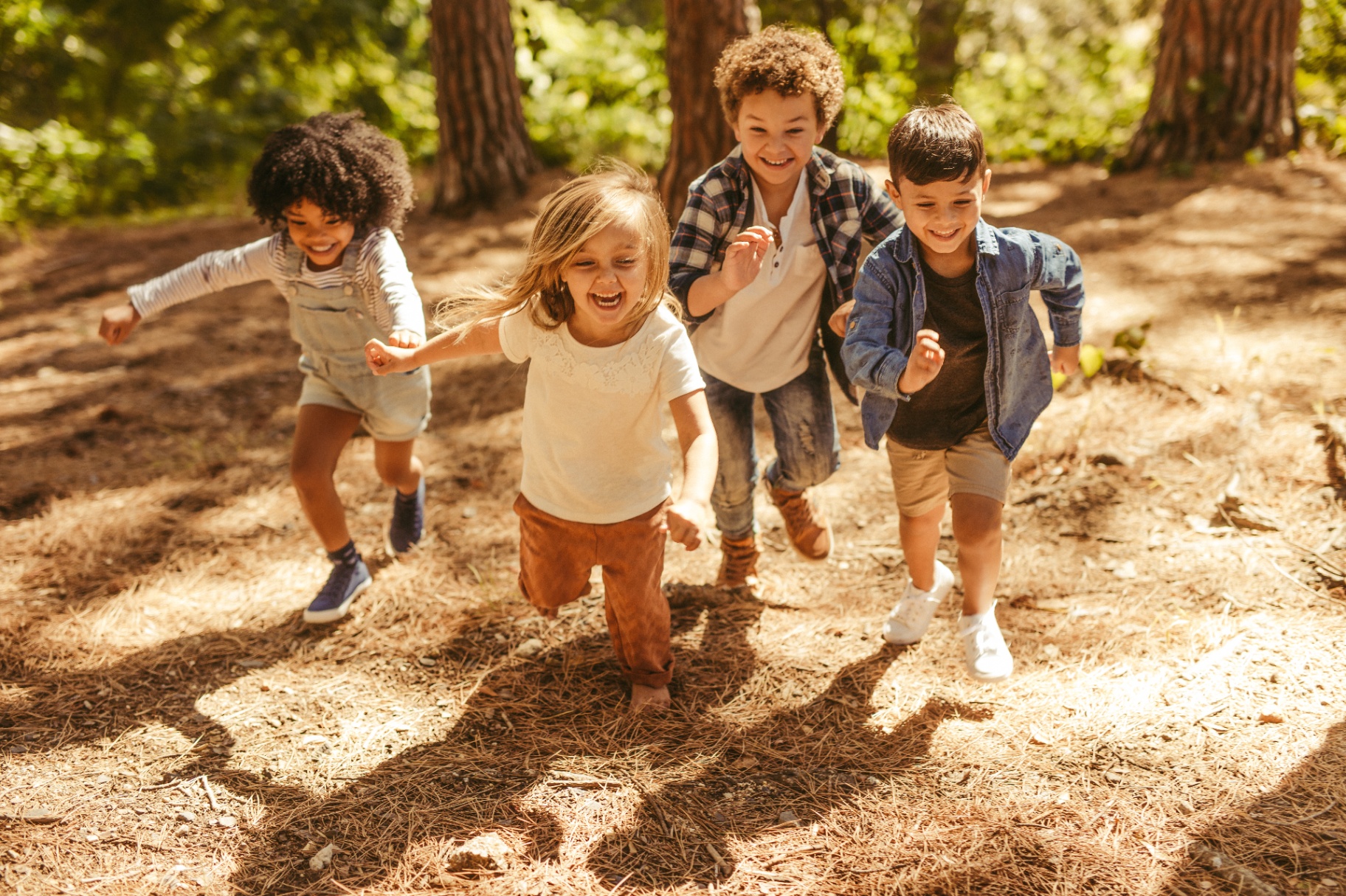 Children running happily through a sunlit forest